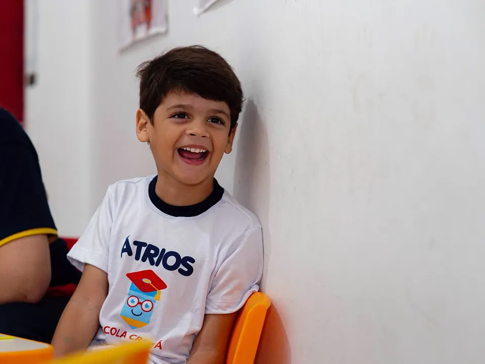 Menino sorrindo com o uniforme da Átrios em sala de aula