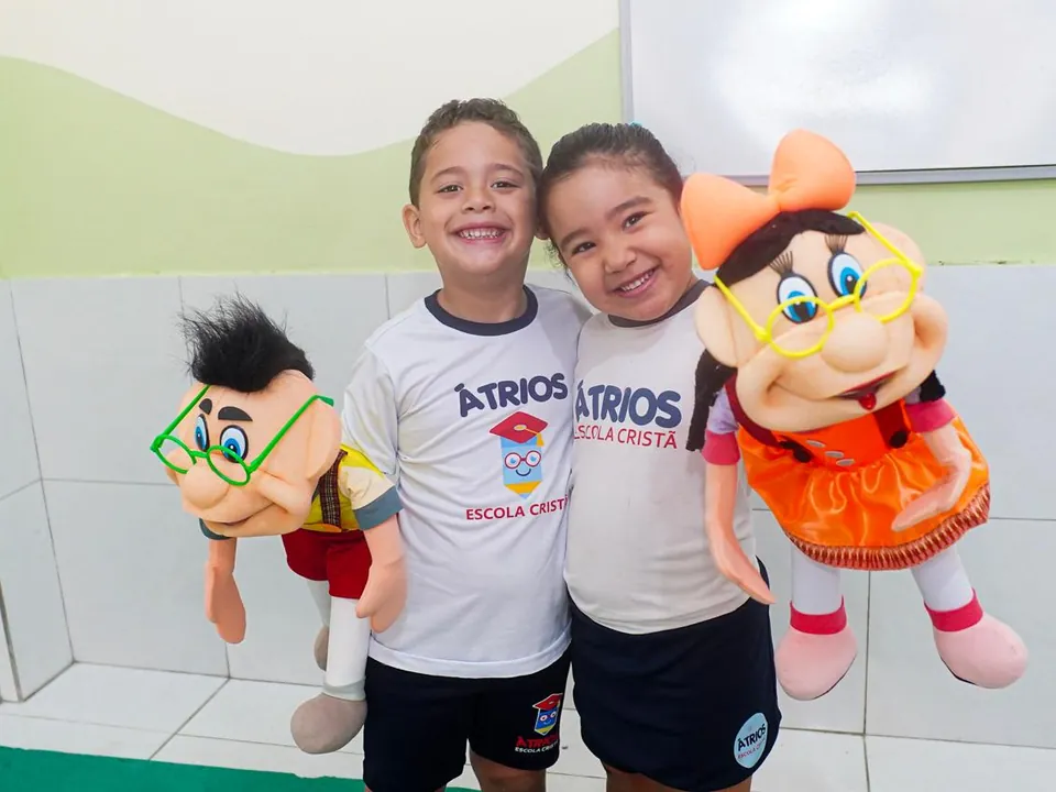 Dois amigos sorrindo com fantoches na escola